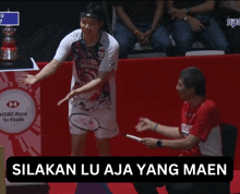 a man in a red shirt stands next to a badminton player in front of a hsbc race to finals banner