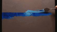 a person is painting a blue line on a canvas with a spatula .