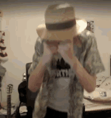 a man wearing a hat and a shirt is covering his eyes .