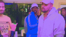 a man in a white hat stands next to a man in a blue jacket that says end i 'm ass