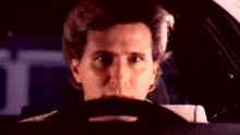 a man is sitting in a car covering his face with his hand