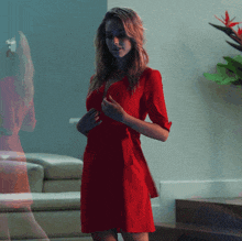 a woman in a red dress is standing in a living room