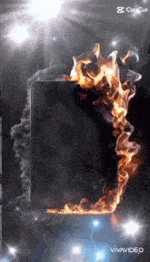 a cell phone is surrounded by flames and smoke on a black background .