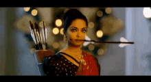 a woman is holding an arrow in her mouth and a bow and arrow in her hand .