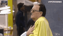 a man wearing sunglasses and a yellow shirt is being held by another man .