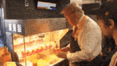 a man standing in front of a display of french fries with a screen that says ' lg ' at the top