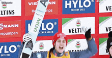 a person holding a skis in front of a wall that says hylo