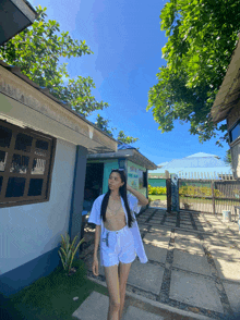 a woman in white shorts stands in front of a building with a sign that says ' tropical paradise ' on it