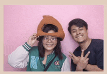a man and a woman are posing for a picture with a pink background ..