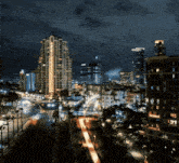 an aerial view of a city at night with a tall building that says ' the ritz carlton ' on it