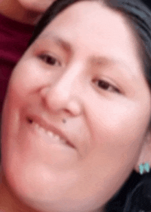 a close up of a woman 's face smiling and looking at the camera