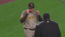 a baseball player in a san diego uniform is talking to a referee on a baseball field .