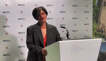 a woman stands behind a podium with bristol written on the wall behind her
