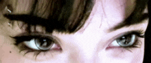 a close up of a woman 's eyes with black eyeliner and a piercing .