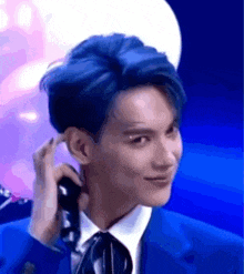 a man with blue hair is wearing a blue suit and tie .