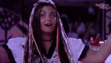 a woman with long hair and a crown on her head is standing in front of a crowd .