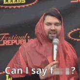 a man wearing a red hooded jacket is holding a microphone and says can i say f ?