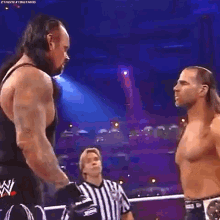 two wrestlers are standing next to each other in a wrestling ring .