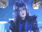 a woman in a blue shirt and black gloves is playing drums