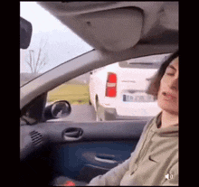 a woman wearing a nike sweatshirt is sitting in a car with her eyes closed