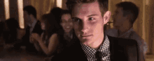 a man in a suit and tie is looking at the camera while sitting at a bar .