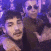 a couple of men are standing next to each other in a dark room .