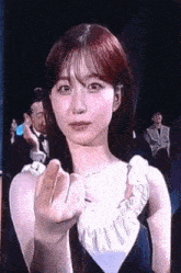 a woman in a blue dress is making a heart sign with her hand .