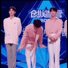 a group of young men are standing on a stage in front of a sign that says ' a '