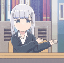 a girl with white hair and green eyes is sitting at a desk