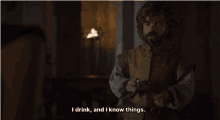 a man with a beard is holding a glass of wine and says i drink and i know things