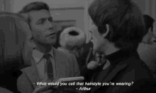 a man in a suit and tie is talking to a woman and says " what would you call that hairstyle you 're wearing