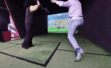 a man is jumping in front of a screen that shows a soccer game going on