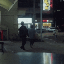 a couple of people walking down a street at night with a sign that says ' nc ' on it