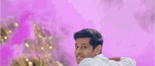 a man in a white shirt is standing in front of a pink wall .