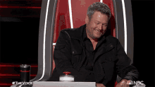 a man is sitting in a chair with a nbc logo on the bottom