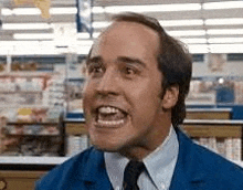 a bald man in a blue jacket and tie is making a funny face .