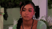 a woman wearing a green shirt and earrings looks at the camera .