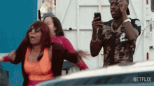 a man is holding a cell phone while standing next to a group of people .