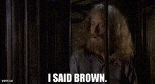 a man is standing in front of a cage with the words `` i said brown '' written on the bottom .