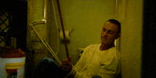 a man is tied up with a rope in a room with a can of propane in the background