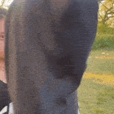 a man in a black hoodie is standing in a field with his arm in the air .