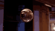 a glass ball with a reflection of a building is floating in the air