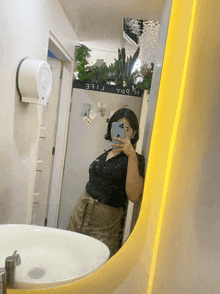 a woman is taking a picture of herself in a bathroom mirror with a sign on the wall that says " y99 "
