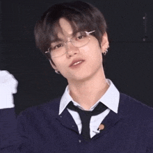a young man wearing glasses and a tie is giving a thumbs up sign .