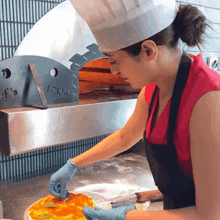 a woman in a chef 's hat prepares a pizza in front of an oven that says forno
