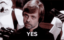 a man with a beard is sitting in front of a group of stormtroopers .