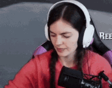 a woman is wearing headphones and sitting in front of a microphone .