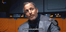 a man with a beard says people are predictable in a dark room