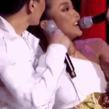 a woman singing into a microphone while a man holds her neck