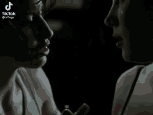 two women looking at each other in a dark room with a tiktok watermark